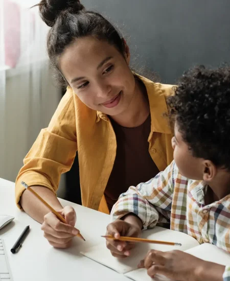 Une dame aide un élève à faire ses devoirs